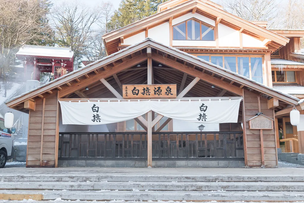 Timber public bathhouse with a white noren curtain over the entrance